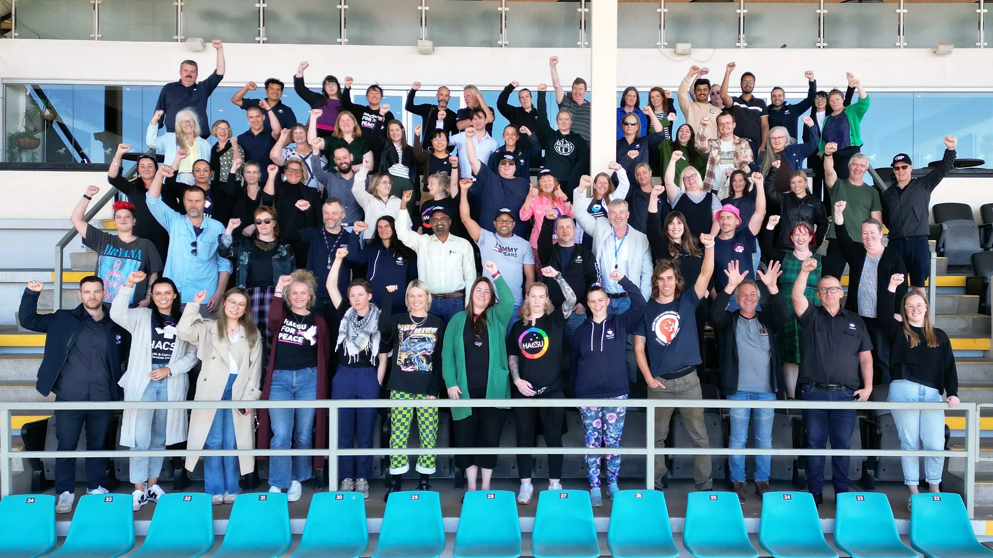 Group photo of HACSU union members working in mental health, with their fists raised in solidarity.