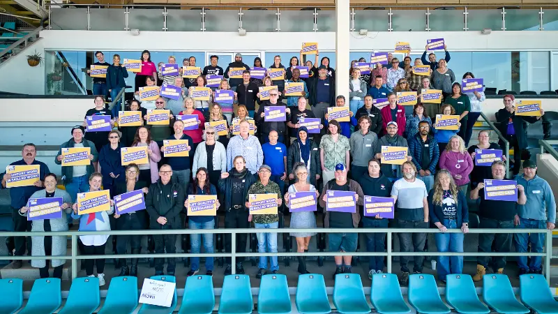 Group photo of HACSU union members outdoors holding signs for Support Disability Support Workers campaign and NDIS advocacy.